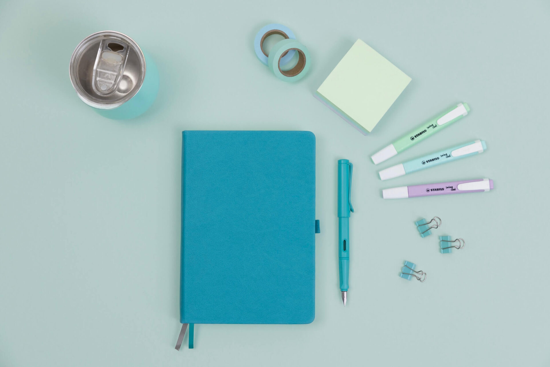 Some pens, post its and washi tape in shades of blue, purple, and green, which are Words by Bonnie's brand colours. There's also a blue notebook where Bonnie might plan her fixed- 9- grid on Instagram