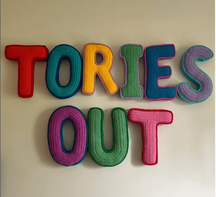Colourful crochet capital letters spell "TORIES OUT".