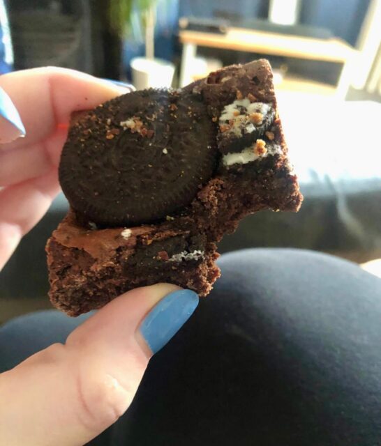 Close up picture of a square of brownie with a bite taken out of it. 